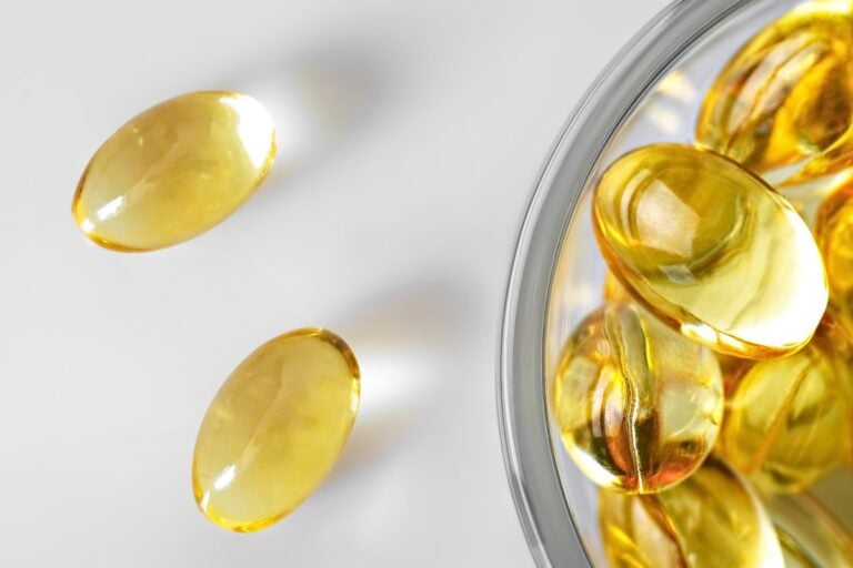 Golden fish oil capsules in a small glass bowl